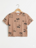 Front view of an H&M brand brown short-sleeved t-shirt for infants, featuring a continuous pattern of black outline drawings of safari animals like giraffes, zebras, lions, and palm trees. It is hanging on a wooden hanger.