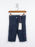 A pair of navy blue infant cargo pants by Girlstar hanging on a pink and white clip hanger. The pants feature large side pockets with buttons and a white "Adjustable Waistband" tag attached to the waist. The background features the Tiny Thrift Store logo.