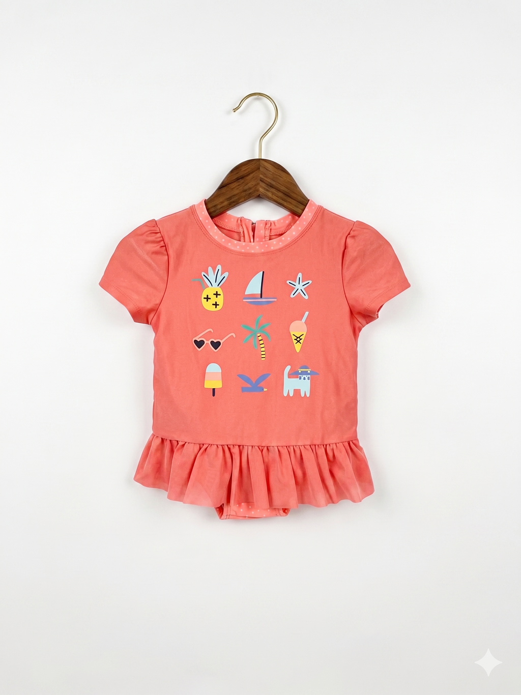 A vibrant coral short-sleeve one-piece swimsuit for toddler girls by Cat & Jack, featuring colorful summer icons like pineapples and sailboats with a peplum ruffle, hanging on a white hanger at Tiny Thrift Store.