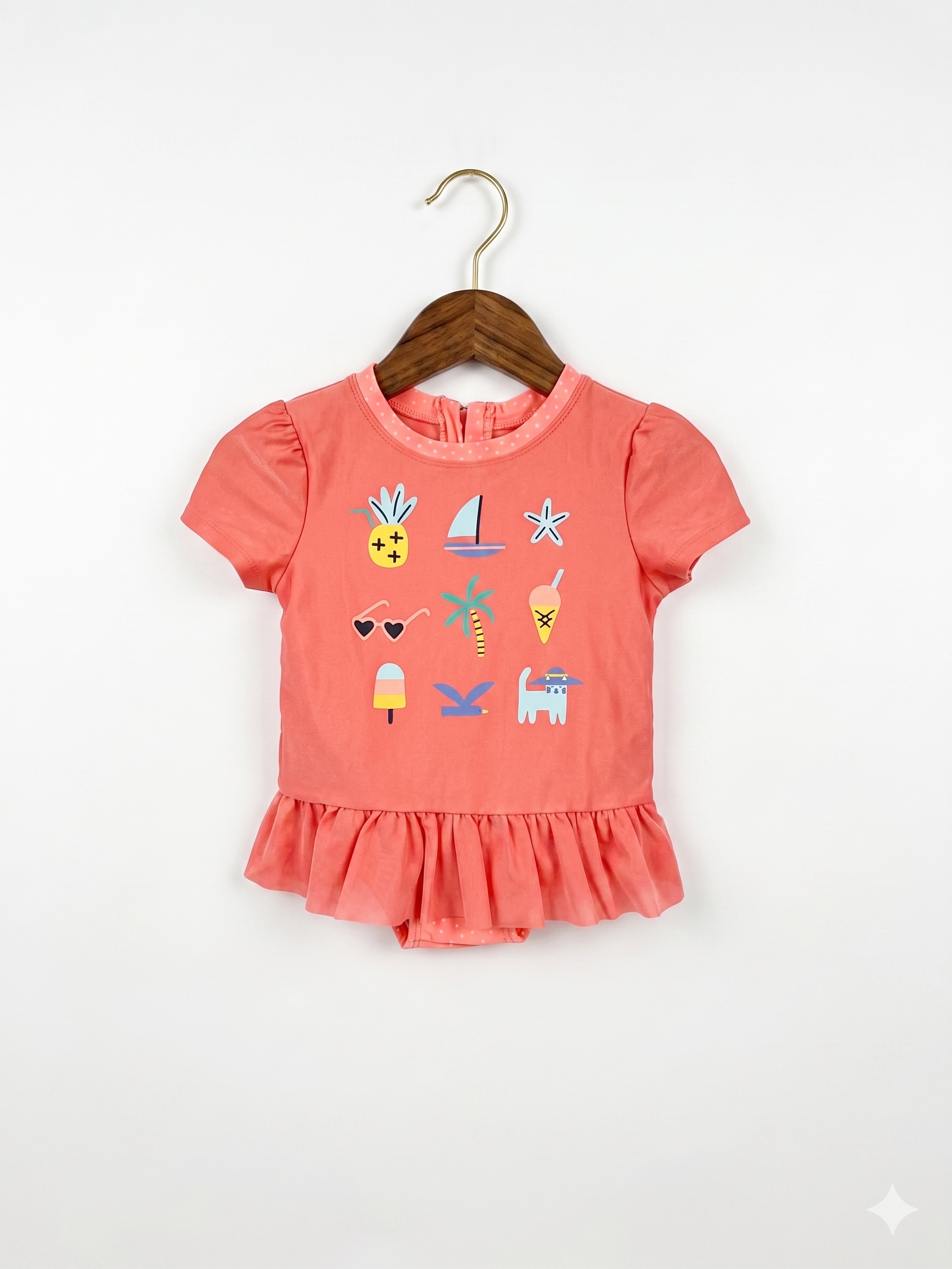 A vibrant coral short-sleeve one-piece swimsuit for toddler girls by Cat & Jack, featuring colorful summer icons like pineapples and sailboats with a peplum ruffle, hanging on a white hanger at Tiny Thrift Store.