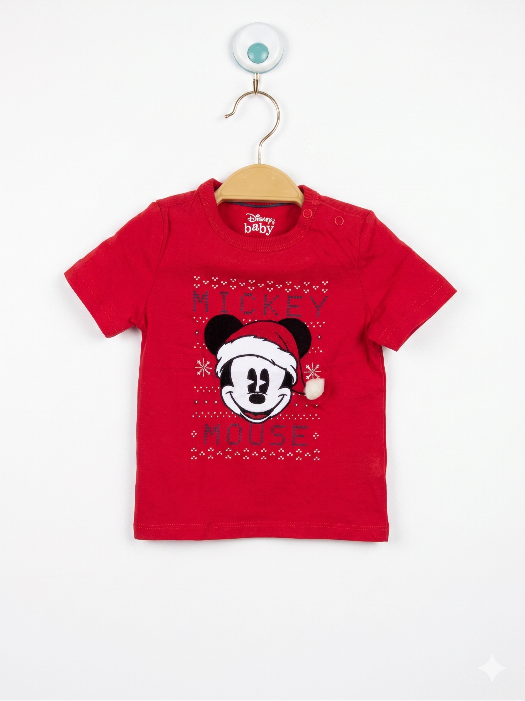 Front and back view of a red infant t-shirt featuring Mickey Mouse in a Santa hat with a white pom-pom. The shirt is displayed on a hanger in front of a Tiny Thrift Store backdrop.