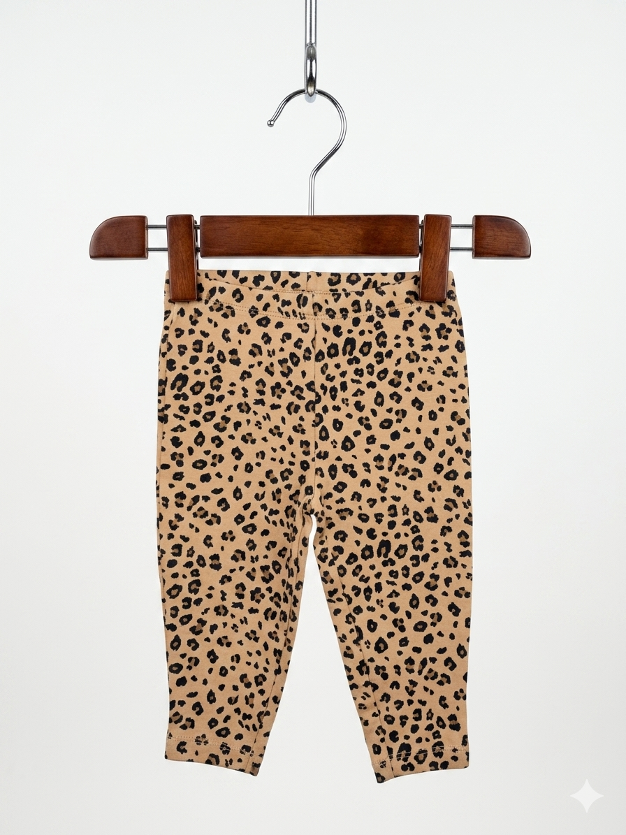 Baby girls leopard print leggings by Carter's, size 9 months, featuring a realistic cheetah pattern on a tan background, hung on a pink hanger against the Tiny Thrift Store backdrop.