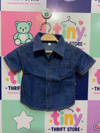 Front and back view of a baby boy's short-sleeve blue denim shirt. It has a collar, buttons down the front, and a small pocket on the left. Close-up shows a white size tag with the number "68".