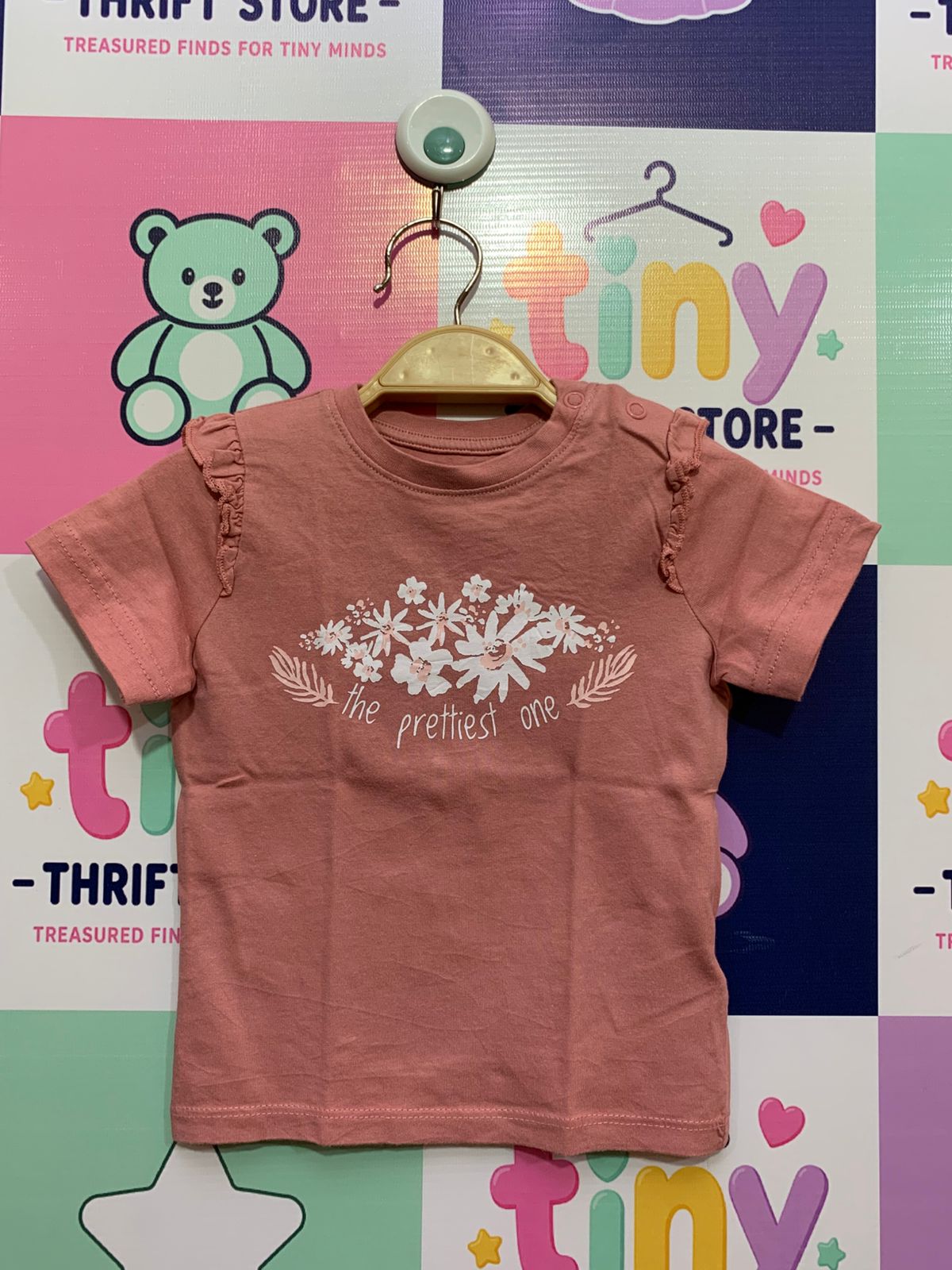 Fox & Bunny by Sinsay baby girl t-shirt in dusty rose pink, featuring white floral graphic with 'the prettiest one' text and shoulder ruffles, size 9-12 months.