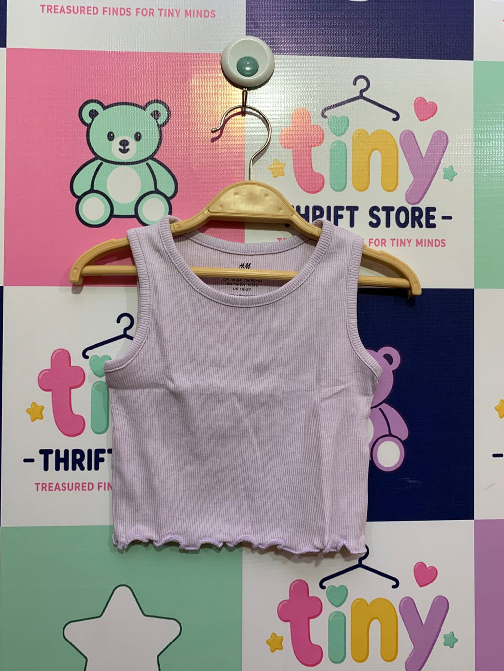 H&M brand toddler girl lilac purple ribbed tank top with lettuce-edge hem on a wooden hanger showing size US 2T EUR 92 label for professional e-commerce store listing.