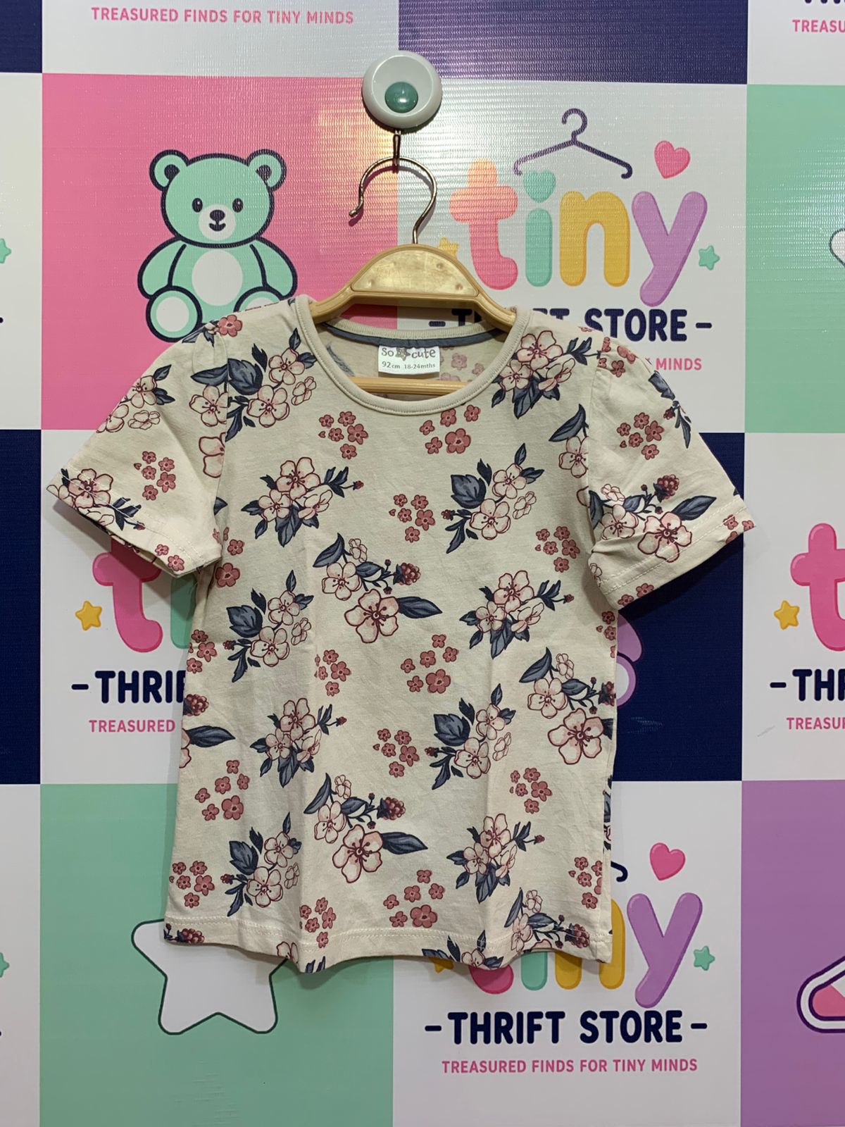So Cute brand toddler girl cream floral t-shirt on a wooden hanger showing size 92 cm 18-24 mths label in a professional studio setting for e-commerce listing.