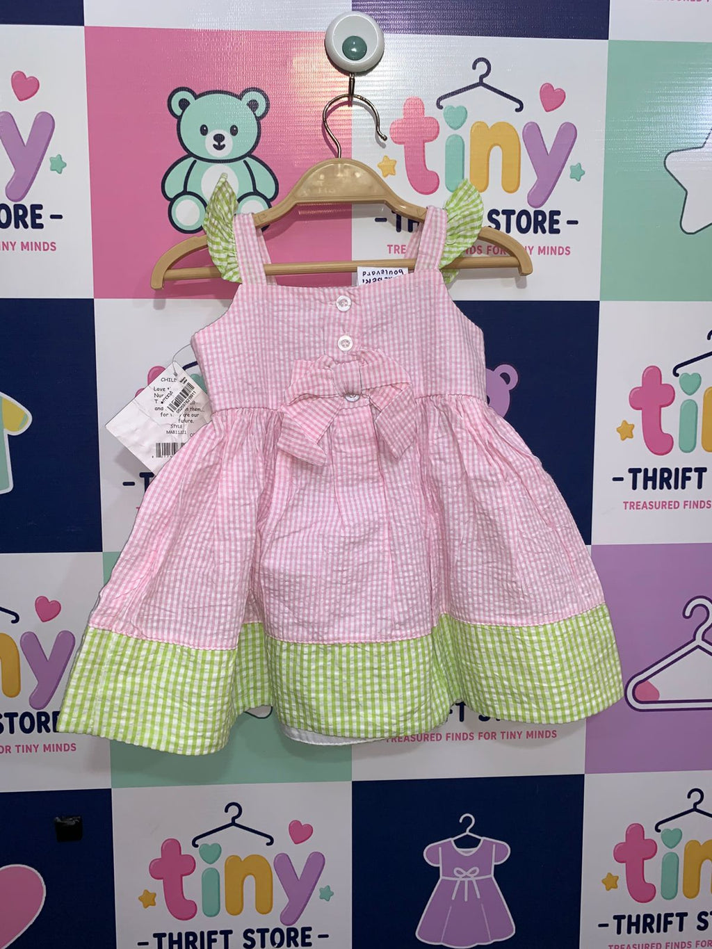 Rear view of infant pink checkered dress featuring a large decorative bow and button-up back.