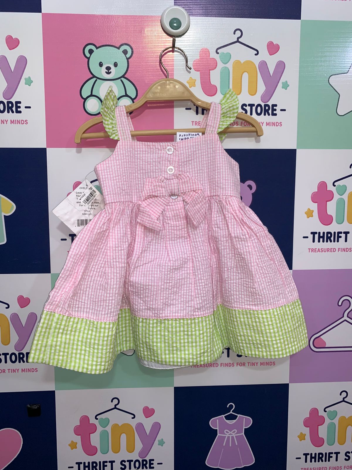 Rear view of infant pink checkered dress featuring a large decorative bow and button-up back.
