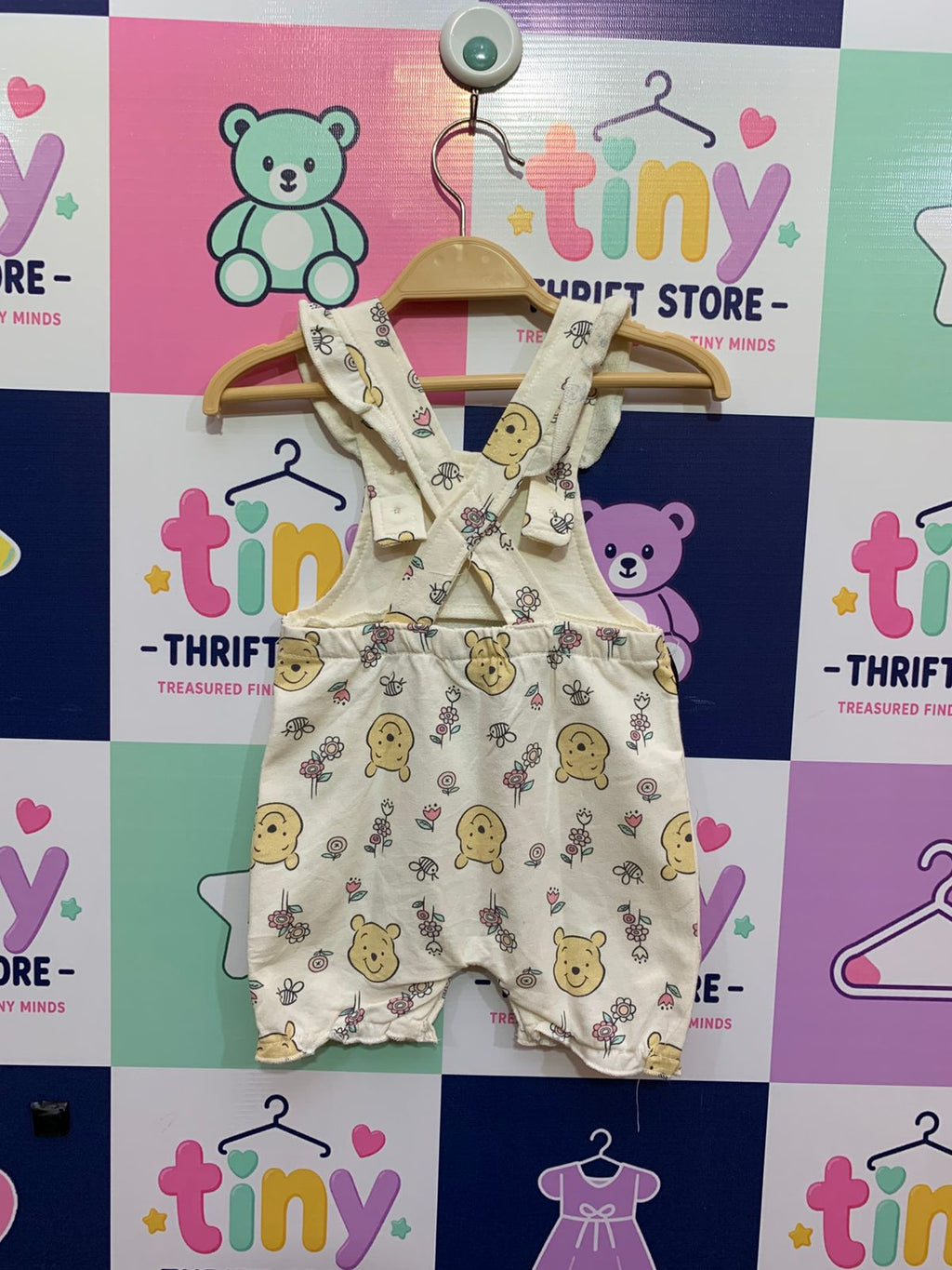 Back of baby Pooh Bear overalls showing the cross-back strap design and elasticated waist.