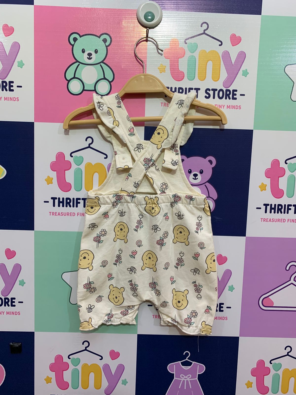 Back of baby Pooh Bear overalls showing the cross-back strap design and elasticated waist.