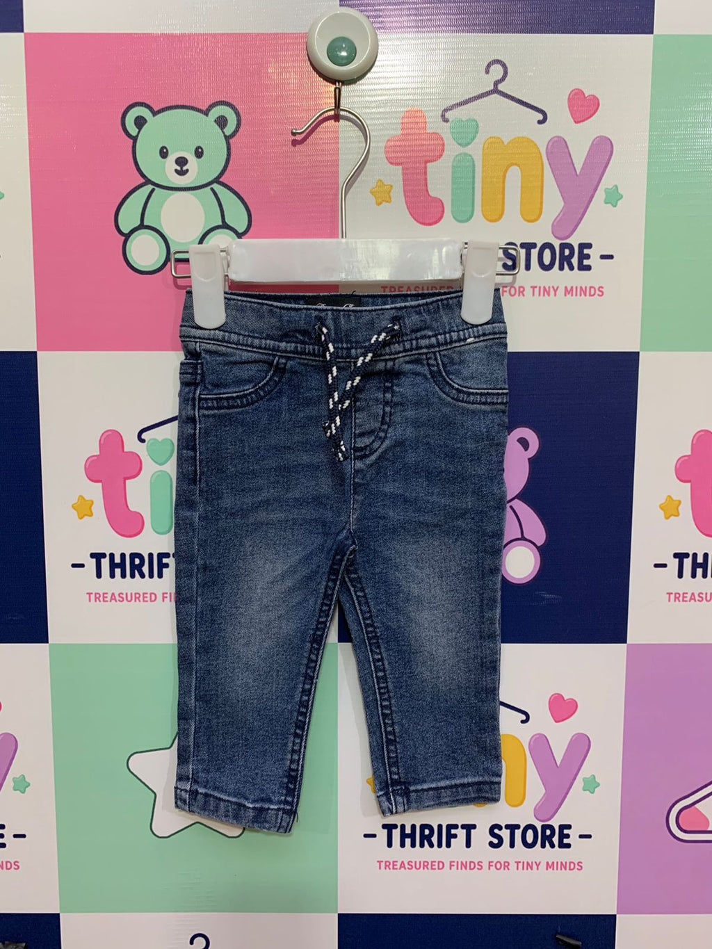 Front view of baby boy Denim Co. blue jogger jeans featuring elastic waistband and drawstring on a white hanger.
