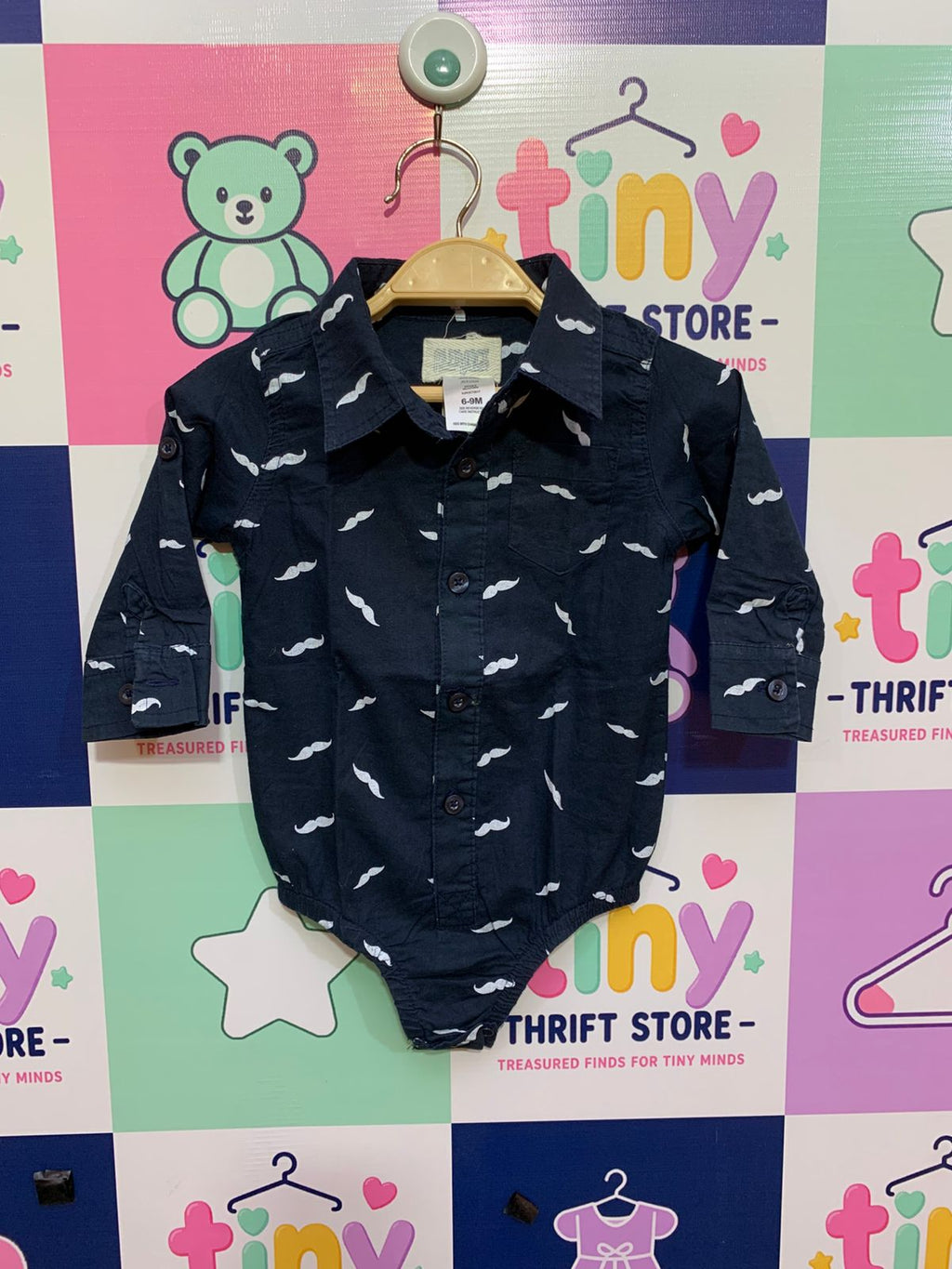 "Infant navy blue long-sleeve shirt bodysuit featuring a white mustache print, button-up front, and 100% cotton material. Brand: Kids with Character, Size 6-9 Months."